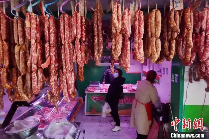 图为顾客在一家肉铺内挑选腊肠。 张远 摄 图片